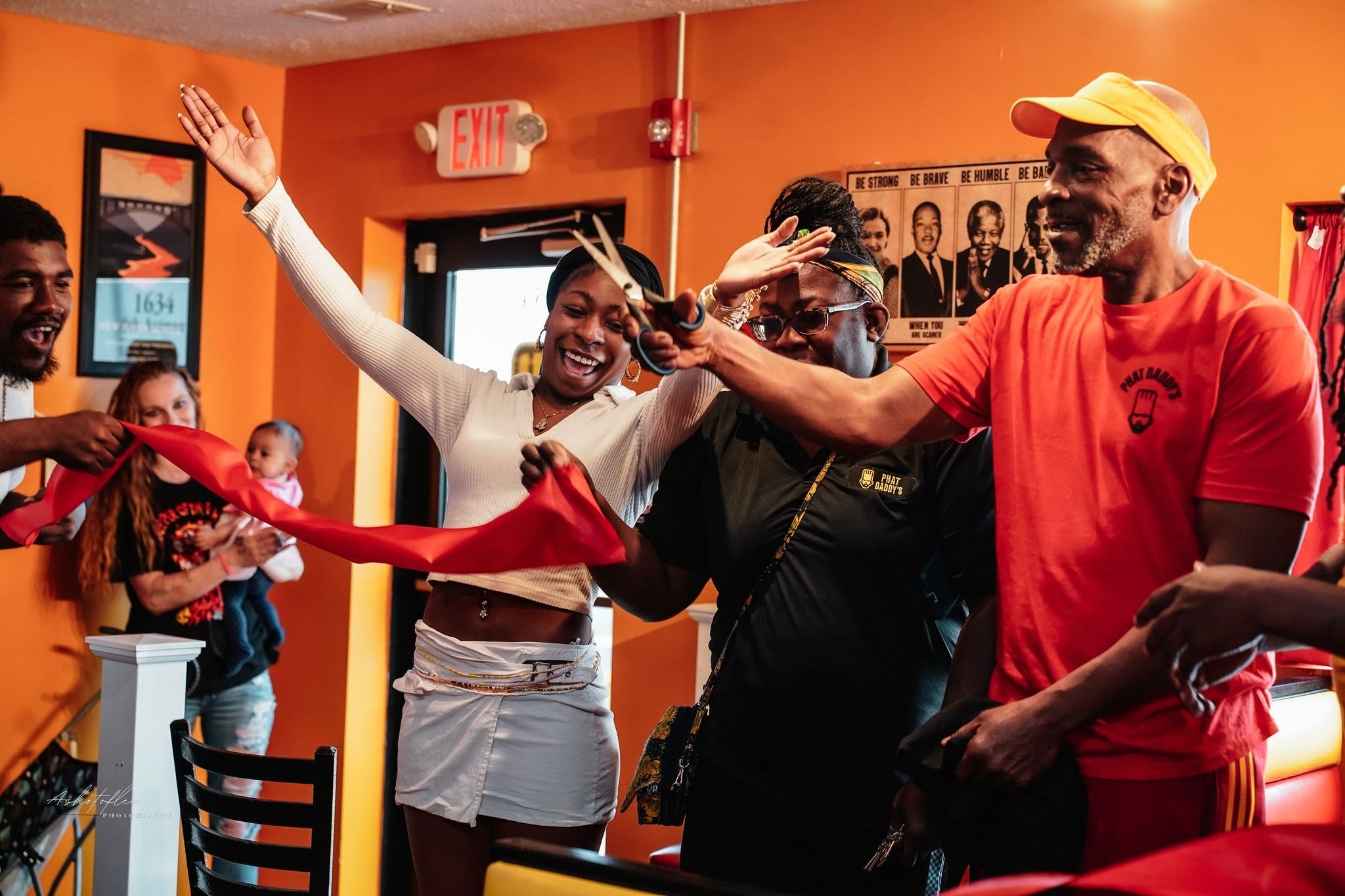 People gathered in a restaurant, cutting a ceremonial ribbon