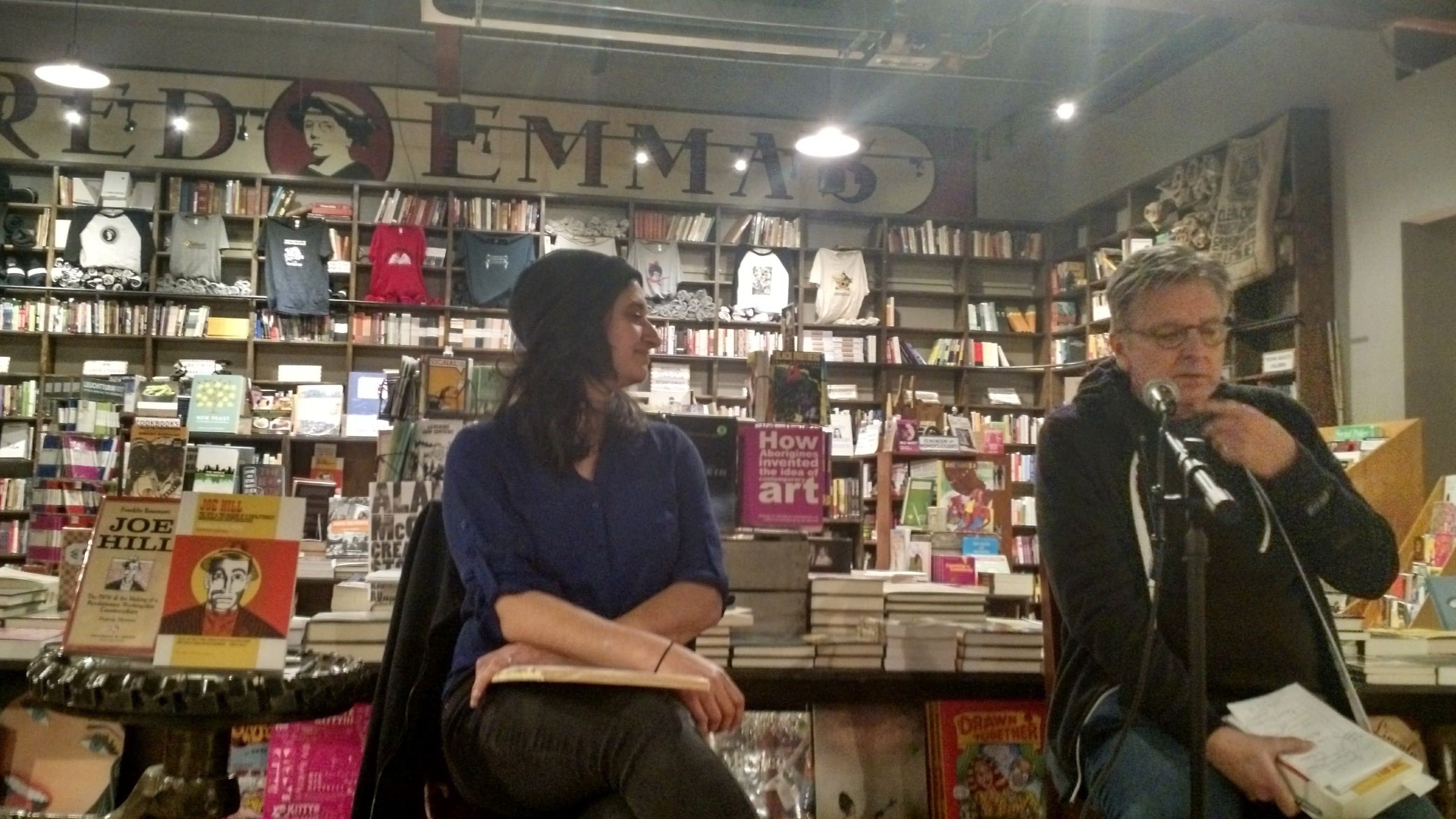 Two people conversing in front of a wall of books