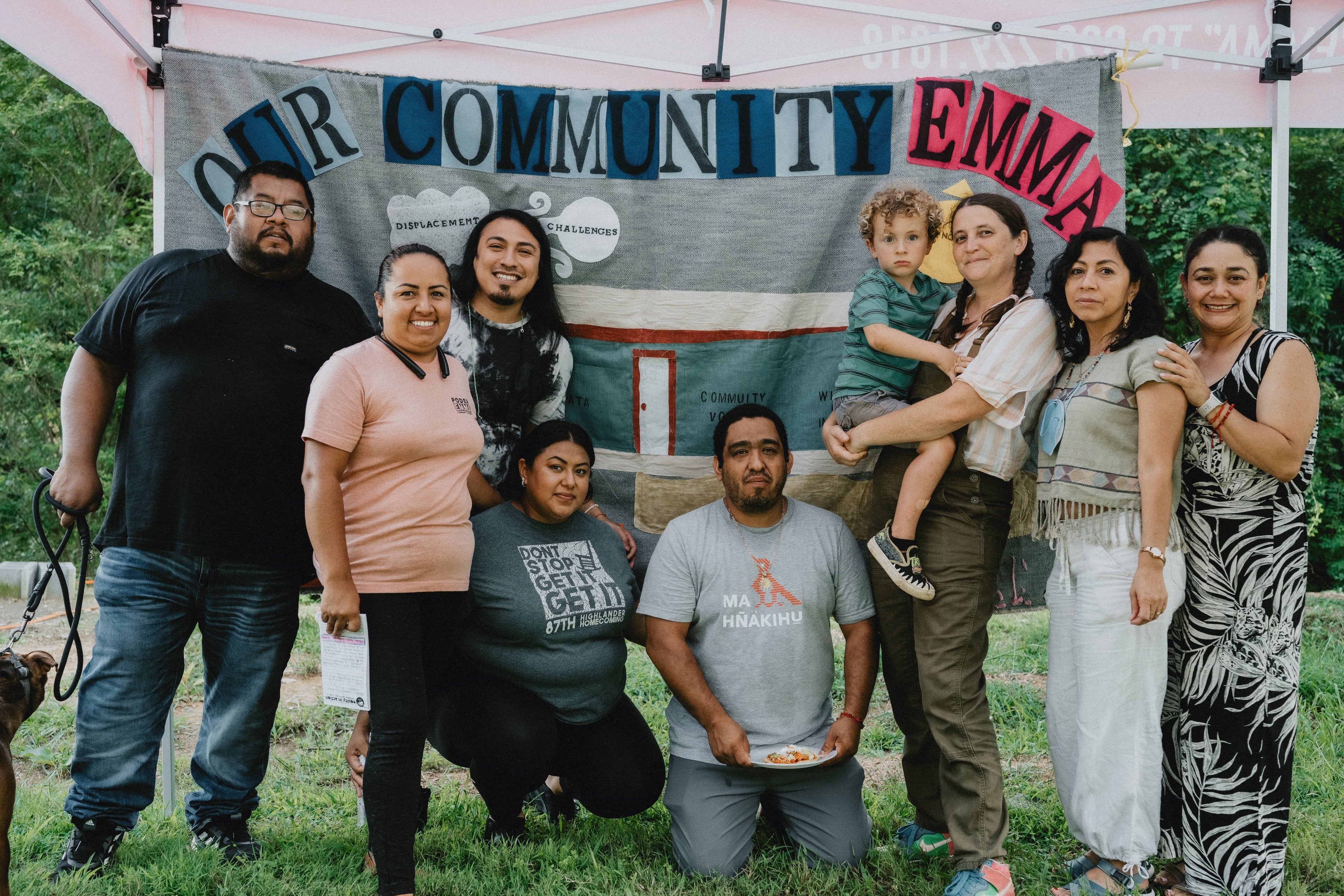 A group of people smiling in front of a banner that reads "Our Community Emma"