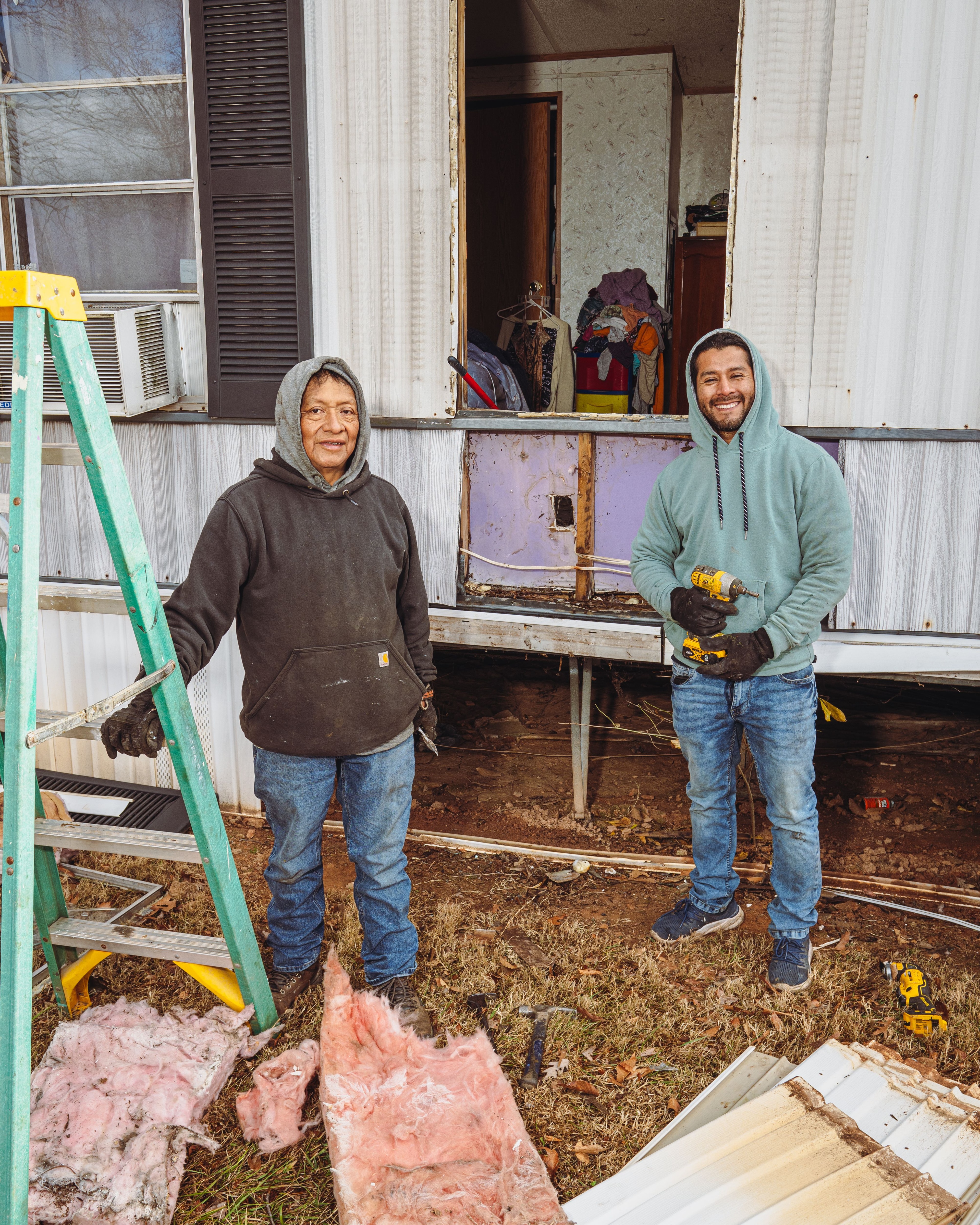 Workers smiling in front of a trailer being repaired