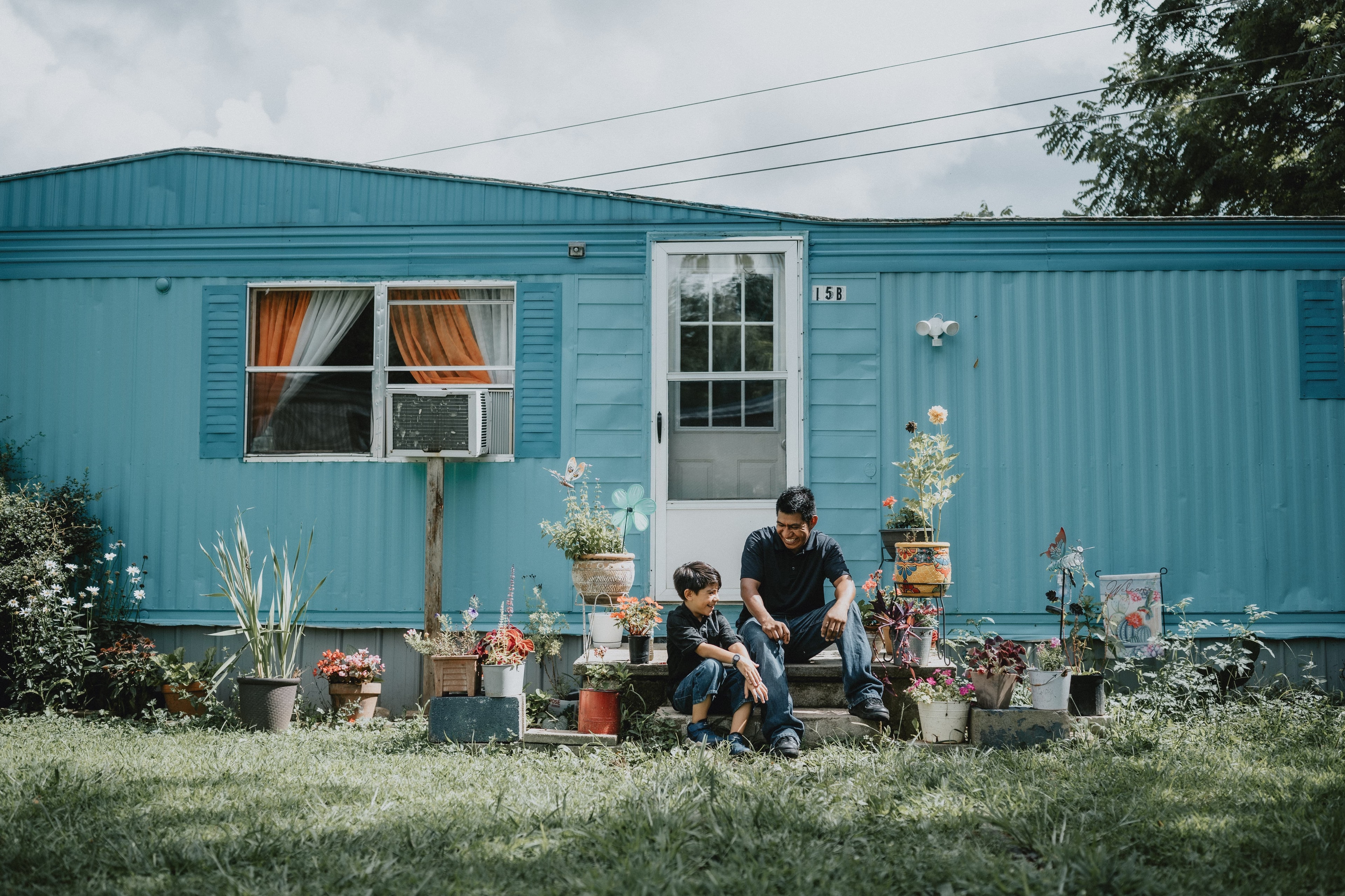 A man and child in front of a modest but incredibly vibrant home