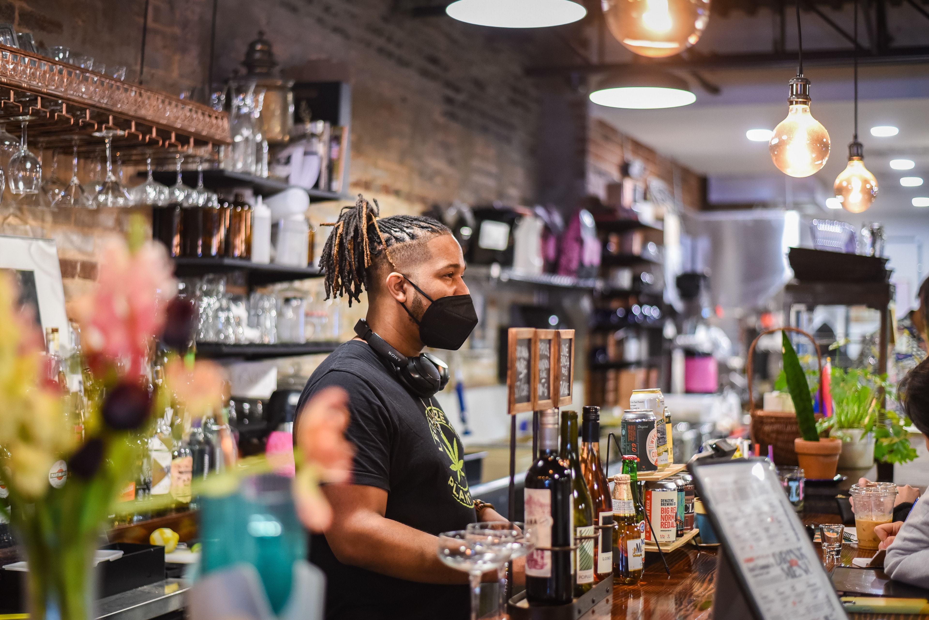 A worker in a mask standing behind a bar counter