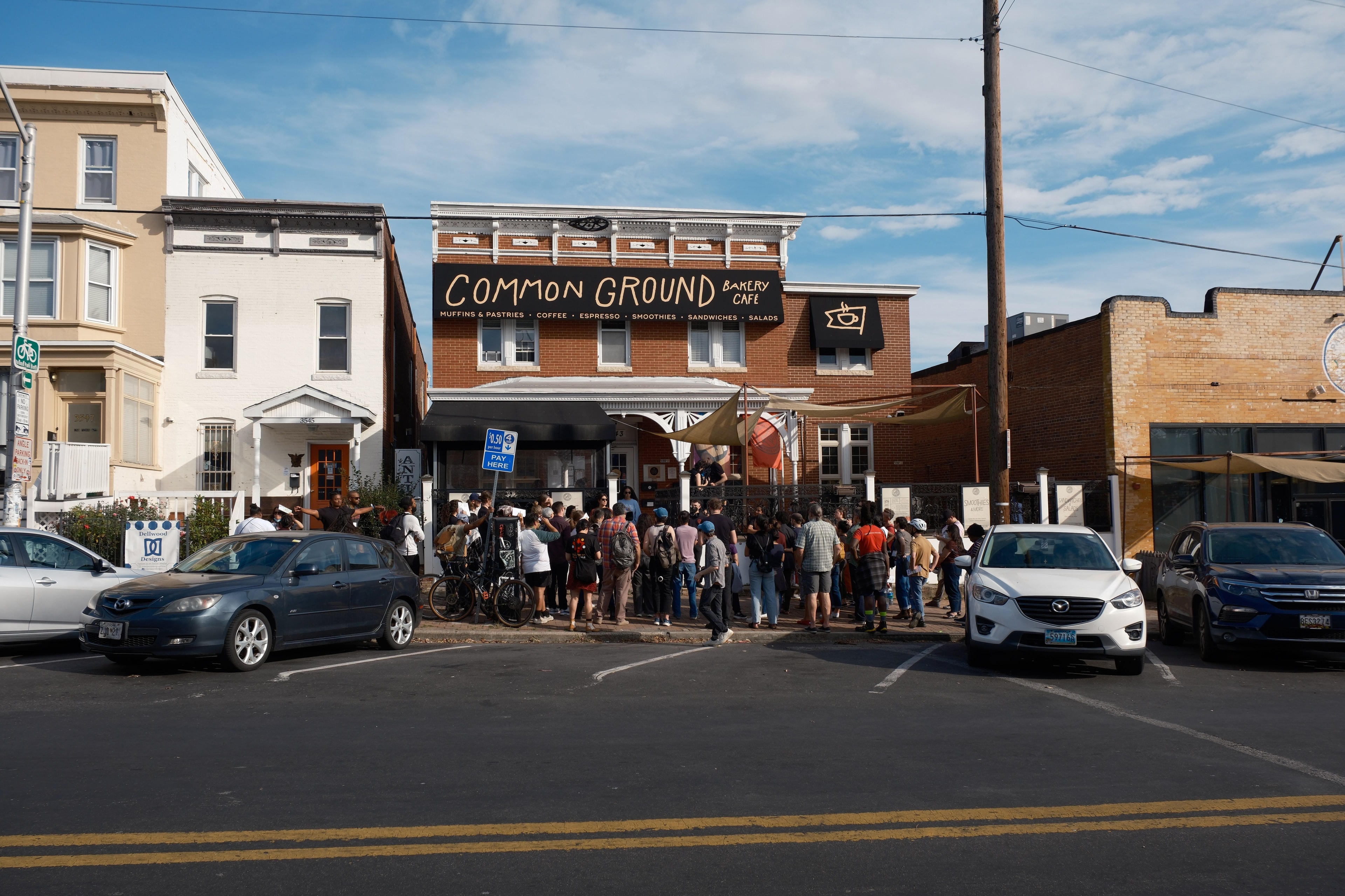 A group of people stand in front of a cafe with a sign that says "Common Ground"